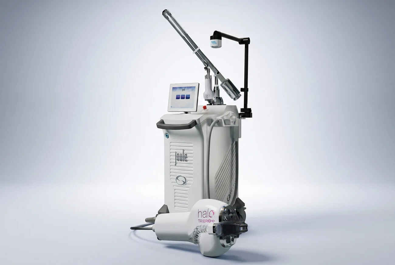 An editorial still life of the Sciton JOULE device and its HALO handpiece, lit and grouped on a warm neutral background.